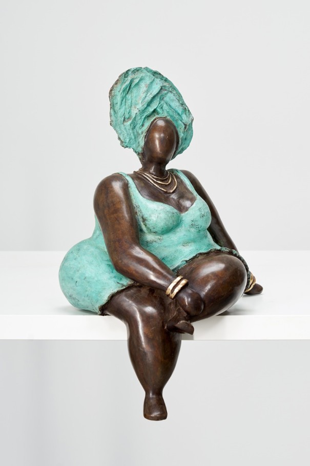 Eine Bronzefigur in einem blauen Kleid und blauer Kopfbedeckung, sitzend.