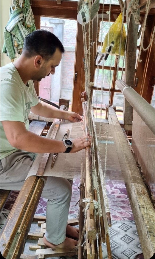 A man at a loom making fabric.