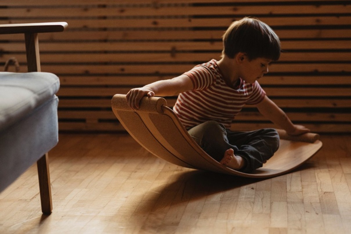 A toddler on a curved wooden board.