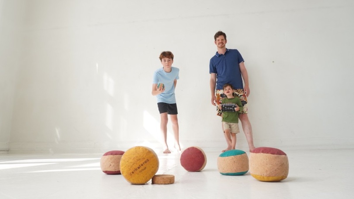 A man and two children playing with balls against a white background. 