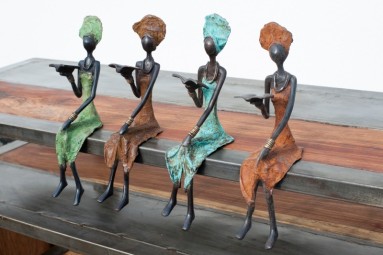 Vier sitzende Bronzefiguren, die je ein Buch in der Hand halten. 
