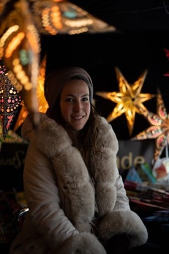 A woman in a fur coat, in the background two paper stars, in the foreground a paper star.