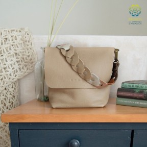 A beige leather bag on a wooden cabinet, next to it are three books.